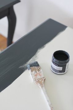 a paint can sitting on top of a white table next to a black and white chair