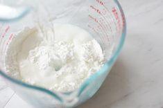 a blender filled with white powder on top of a counter next to a measuring cup