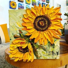 a sunflower painted on a canvas sitting on a table