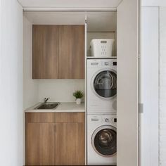 a washer and dryer in a small room with wood flooring, white walls and cabinets