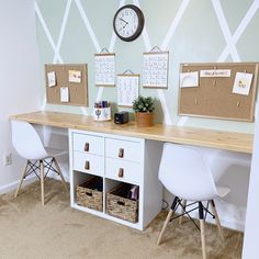 a desk with two white chairs and a clock on the wall above it in an office