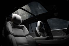 the interior of a vehicle with leather seats and moon in the sky behind it at night