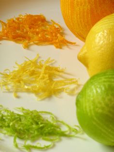 some oranges and lemons are on a white plate with green stuff around them