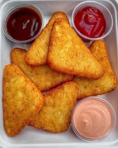 some food in a plastic container with sauces and ketchup on the side