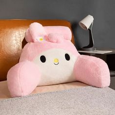 a large pink teddy bear pillow sitting on top of a bed next to a lamp