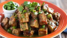 an orange plate topped with tofu and green onions