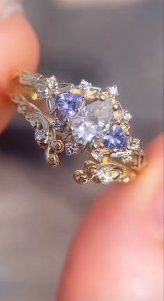 someone is holding a fancy ring with blue and white stones on the side, in their hand