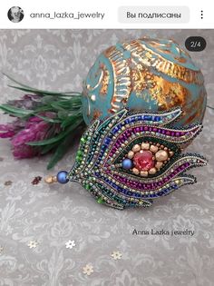 an ornament made out of beads is sitting on a table next to flowers