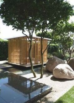 an outdoor area with trees and sculptures in the foreground, along with a small pond