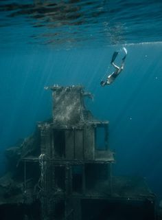 an underwater view of a building in the ocean, with a person swimming near it