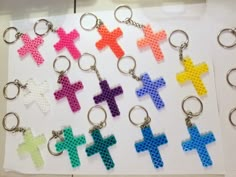 cross keychains made out of perler beads are displayed on a sheet of paper