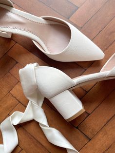 two pairs of white shoes sitting on top of a wooden floor