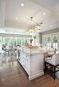 a large kitchen with an island in the middle and chairs around it on the side