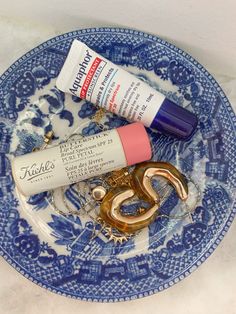 a blue and white plate topped with items like lipstick, toothpaste and scissors