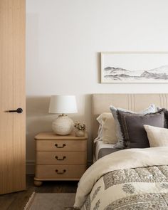 a bed sitting next to a wooden dresser with a lamp on it's side