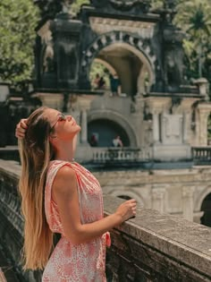 a woman standing on the side of a bridge looking up at something in the air