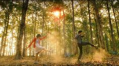 two people are dancing in the woods together