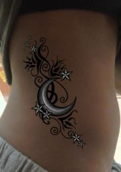 the back of a woman's stomach with an intricate tattoo design on her side