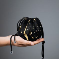 a hand holding a black bag with gold stars and crescents on it's side