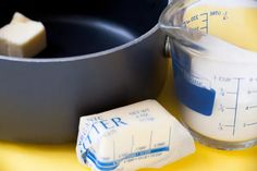 butter and other ingredients are sitting in front of a saucepan on a yellow table