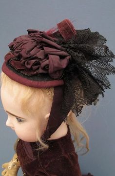 a doll is wearing a brown hat with black lace on it's brim