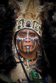 a native american man wearing an elaborate headdress with feathers on his face and nose