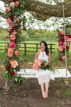 a woman sitting on a swing with flowers around her