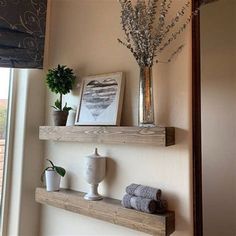 two wooden shelves with plants and towels on them in front of a window sill