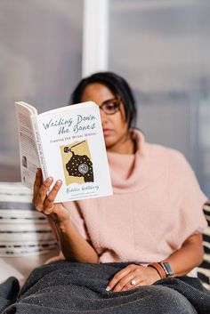 a woman sitting on a couch reading a book