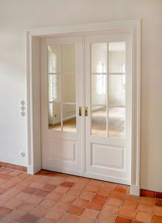 an empty room with two doors and tile flooring in front of the glass door