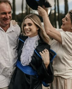 two women and a man are posing for the camera with their graduation gowns on