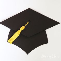 a black graduation cap with a yellow tassel hanging from it's side on a white background