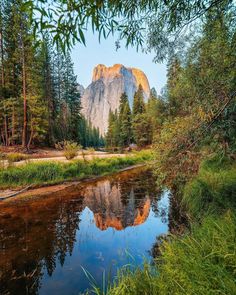 an image of a mountain in the distance with trees around it and water running through the foreground