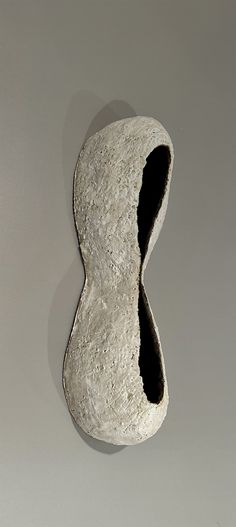 a white sculpture with a black hole in it's center on a gray surface