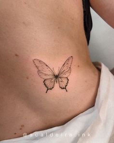 a woman's stomach with a small butterfly tattoo on the side of her belly