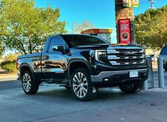 a black truck parked in front of a gas station