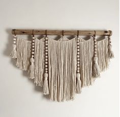 a wall hanging with wooden beads and tassels