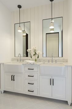 two sinks and mirrors in a white bathroom