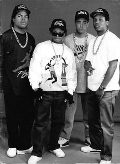 three men standing next to each other in front of a black and white photo with chains on