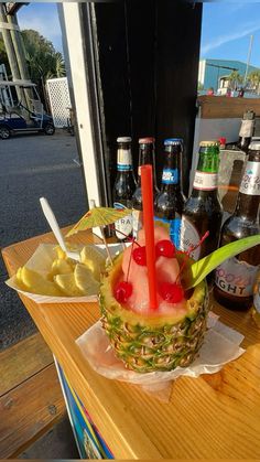 a pineapple is sitting on a table next to some beer bottles and other drinks