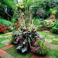 a garden filled with lots of plants and flowers on top of a brick walkway in front of