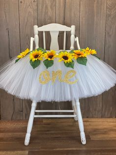 a white chair decorated with sunflowers and the word one on it's tulle