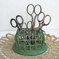 several pairs of scissors are in a green holder on a doily that is sitting on a table