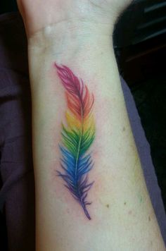 a colorful feather tattoo on the wrist