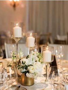 the table is set with white flowers, candles and wine glasses for an elegant centerpiece