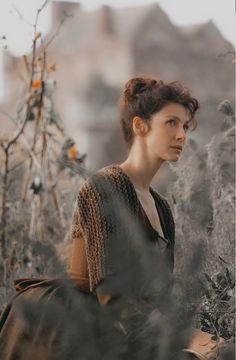 a woman standing in tall grass looking off into the distance