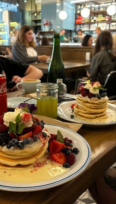 pancakes with fruit and whipped cream are on a table in a restaurant as people sit at the bar