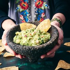 a person holding a bowl filled with guacamole and tortilla chips