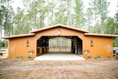 an open barn with lots of trees and flowers on the front door is seen in this image