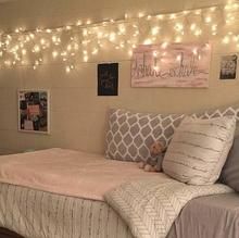 a bedroom with lights strung from the ceiling and a bed in it's corner